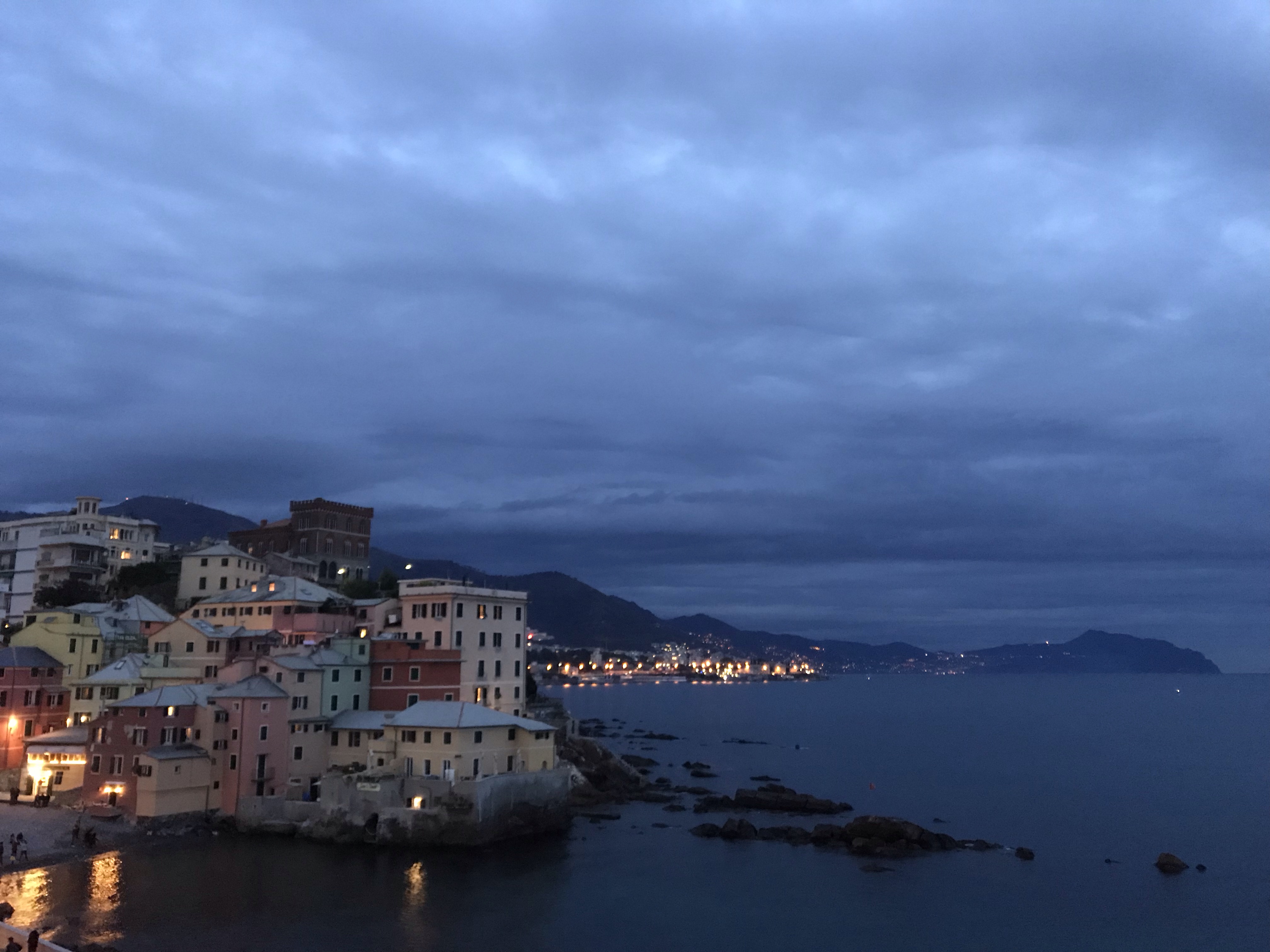 Fotografia del borgo di Boccadasse a Genova verso sera e sullo sfondo il promontorio di Portofino in Liguria, Italia